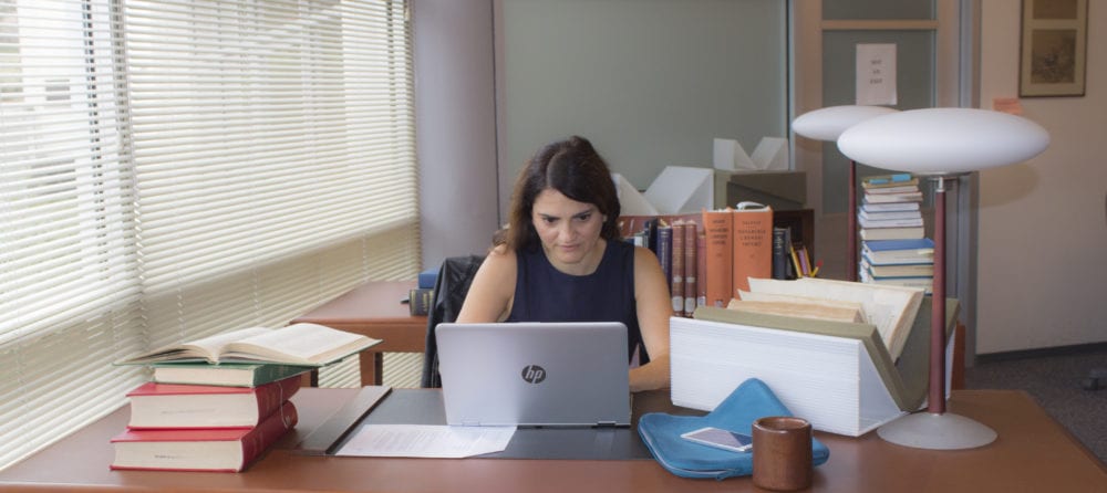 Photograph of former Robbins Fellow Maria Sole Testuzza sitting at a desk in the Robbins Collection Reading Room