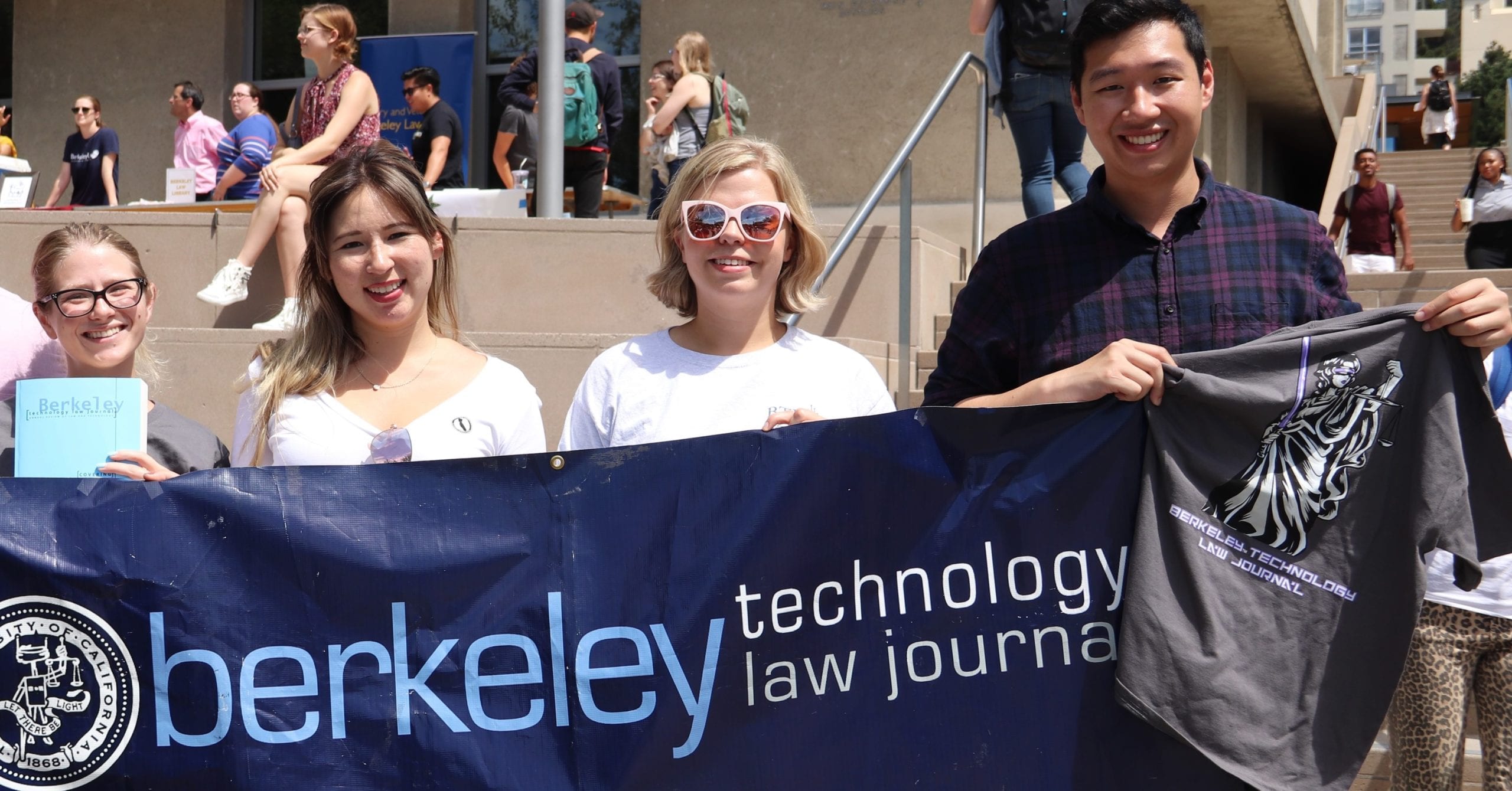 A group of students hold a Berkeley Center For Law & Technology banner at an outdoor event