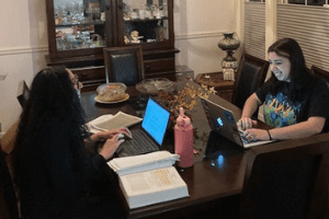two women with laptops at dining table