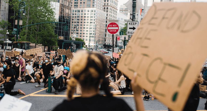 people protesting with "defund the police" sign