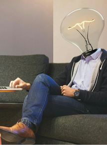 man with light bulb for a head working on laptop