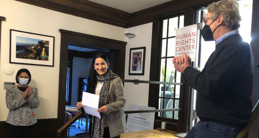 woman walking into room with a man and a woman applauding