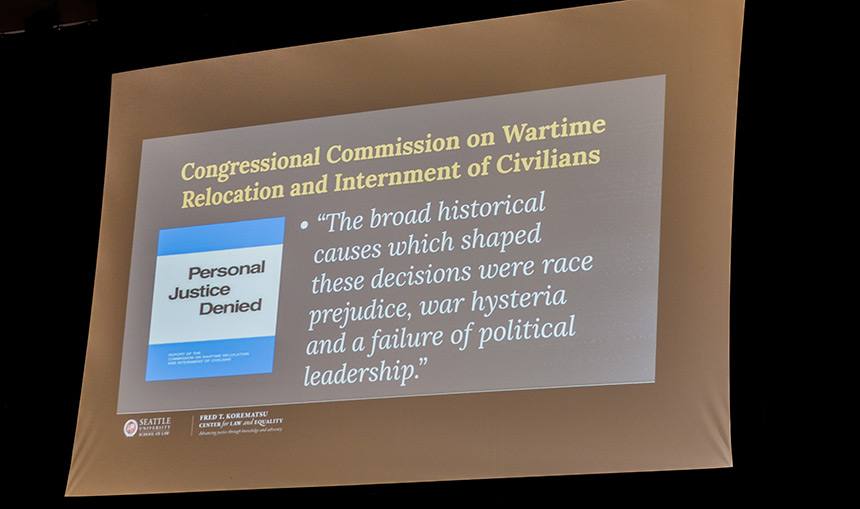 Projected slide showing Congressional Commission on Wartime Relocation and Internment of Civilians quote: The broad historical causes which shaped these decisions were race prejudice, war hysteria and a failure of political leadership.