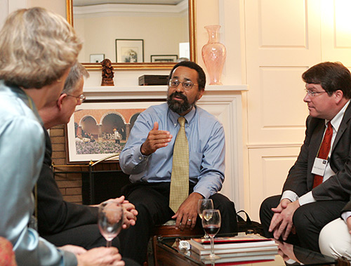 Christopher Edley speaking animated to a small group of people at a reception