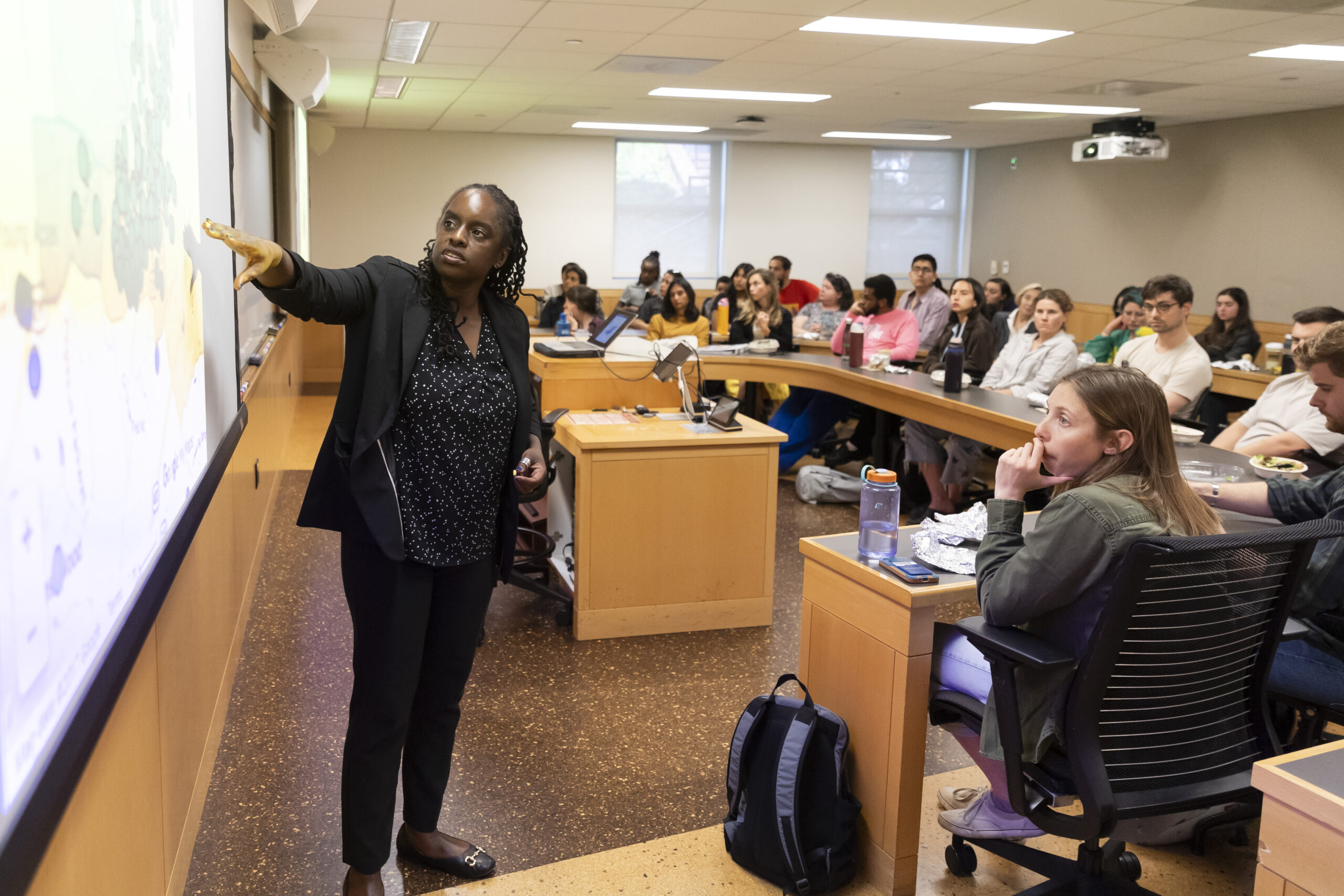 woman at whiteboard presenting to room full of students
