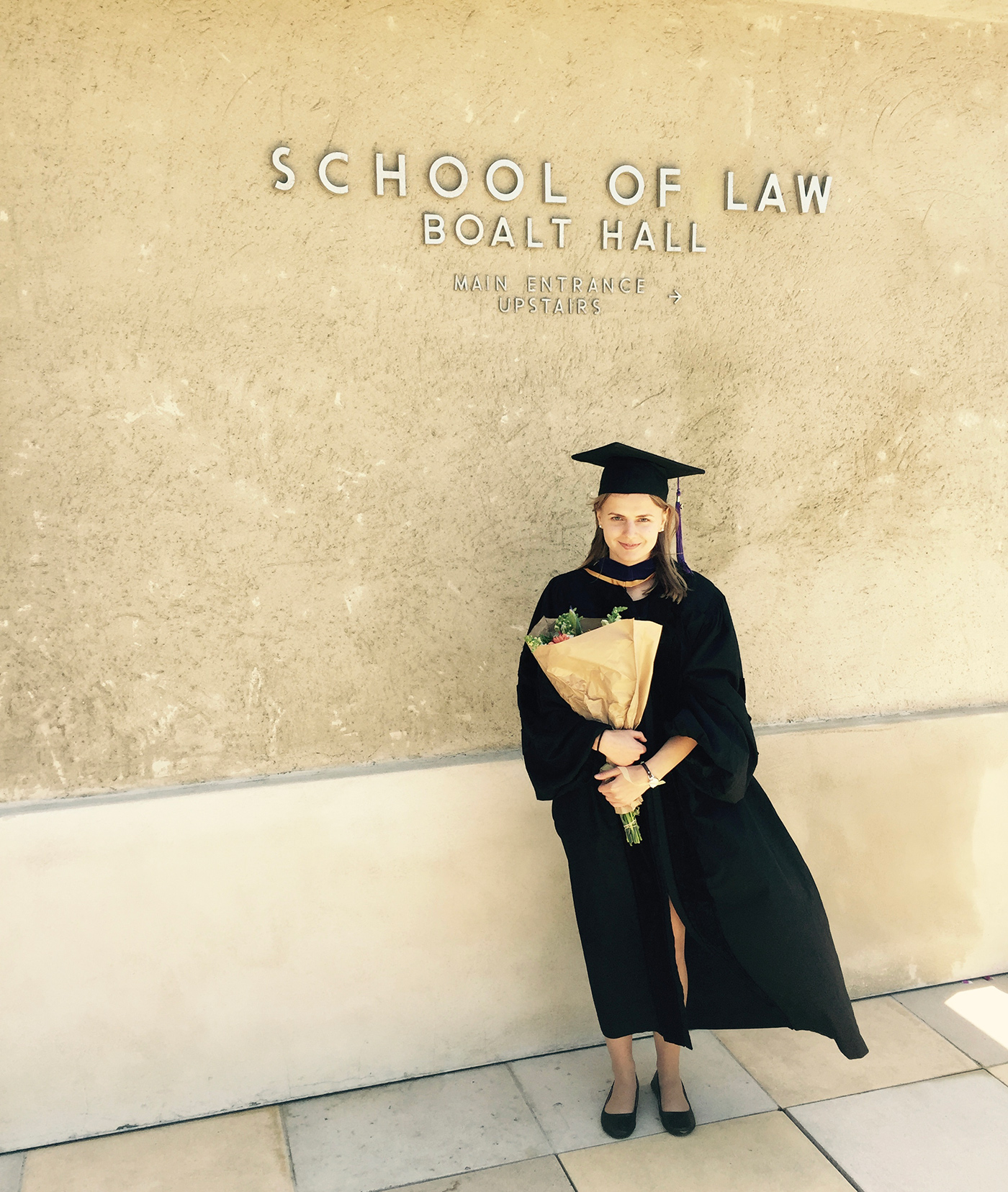 Poudel in graduation gown in front of UC Berkeley sign